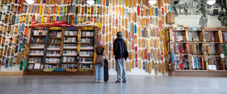 A man and a woman standing in front of a wall of books.