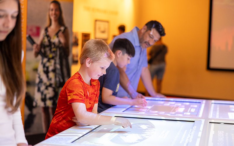 Children and an adult engage with interactive displays in a museum setting, discovering one of the exciting things to do in Simi Valley.